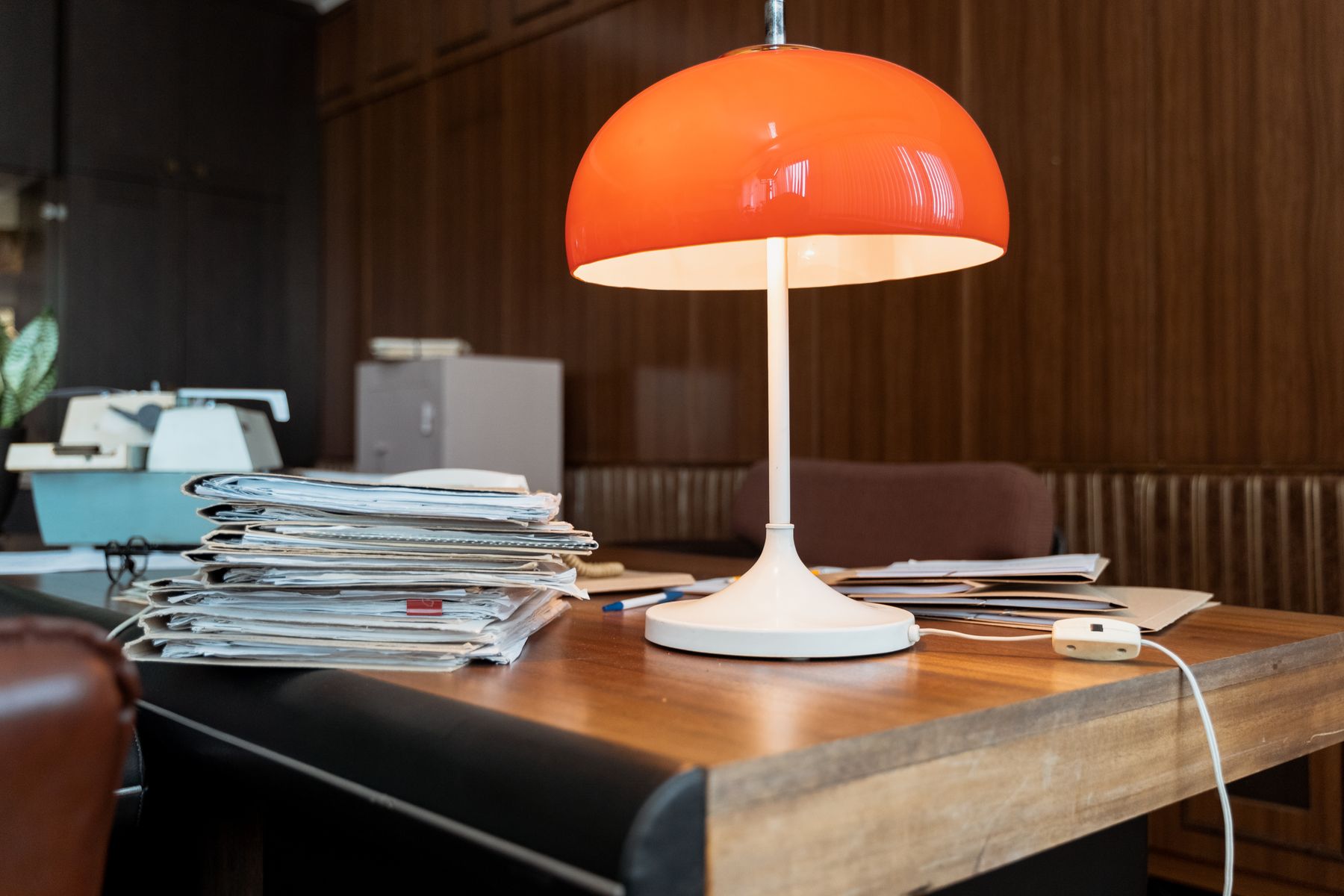Dossiers et documents organisés sous lampe orange sur bureau en bois