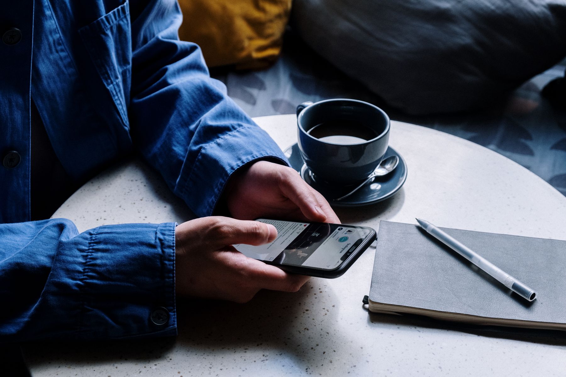 Main écrivant sur un carnet près d'un téléphone et d'une tasse de café