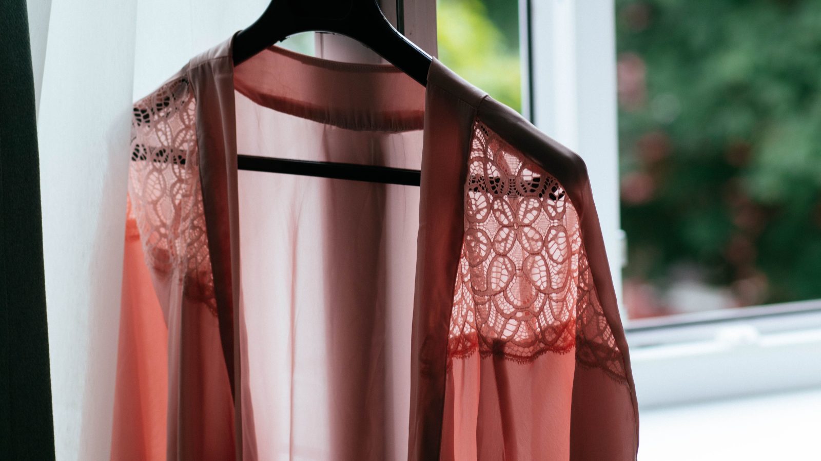Kimono en dentelle rose suspendu près d'une fenêtre
